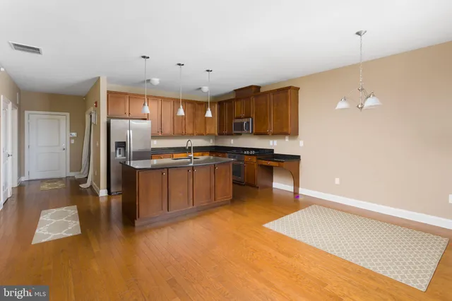 a kitchen with stainless steel appliances granite countertop a refrigerator a stove and a sink