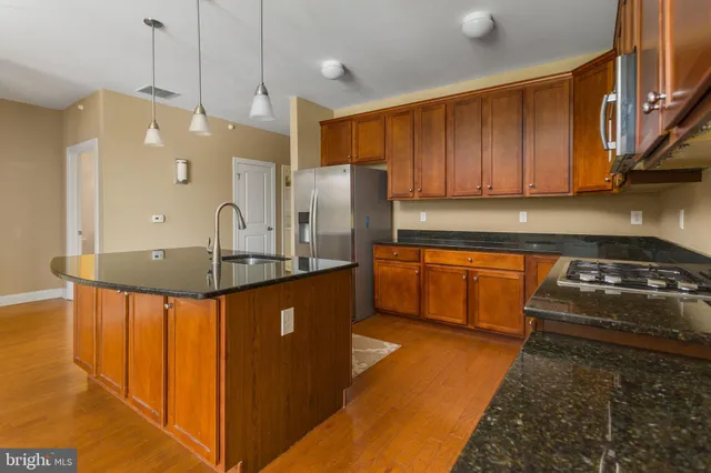 a kitchen with stainless steel appliances granite countertop a sink a stove and a refrigerator