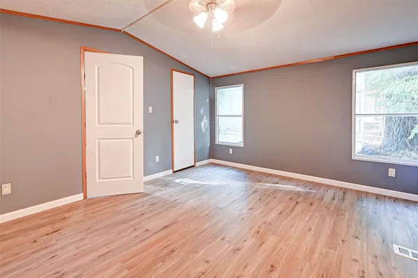 an empty room with wooden floor and windows