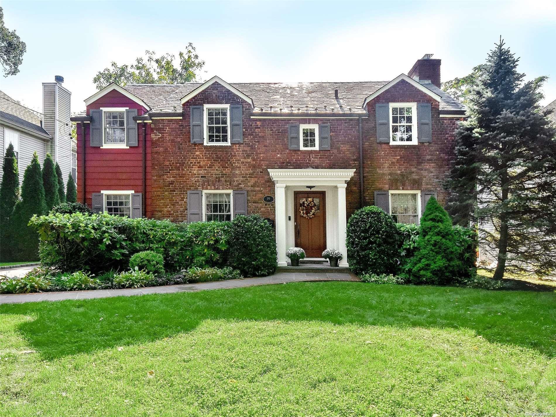 a front view of a house with a yard and trees