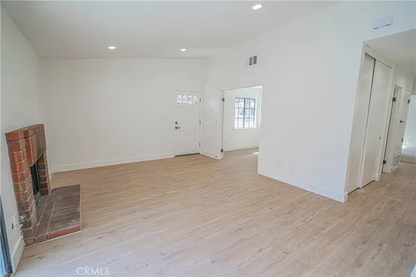 an empty room with wooden floor & windows