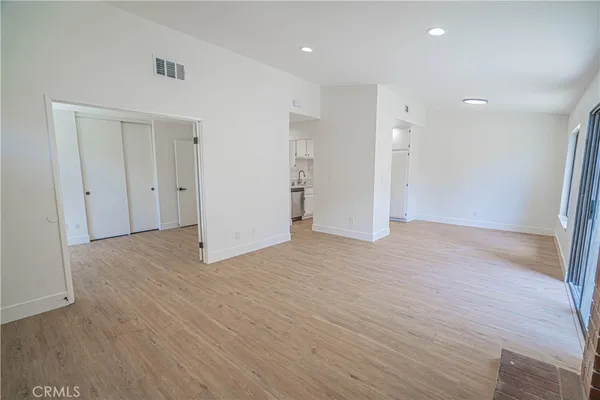 an empty room with wooden floor fireplace and windows