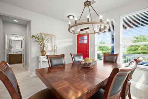 a view of a dining room and livingroom with furniture wooden floor a chandelier