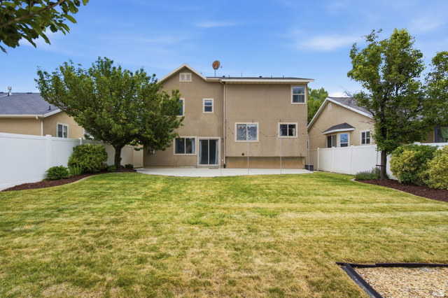 2223 North Pointe Meadow Loop Lehi, UT 84048 - Photo 44 of 56 Spacious backyard featuring a large concrete patio, expansive lawn area, mature trees, and white privacy fencing