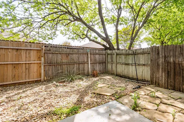 a view of backyard with wooden fence and large trees