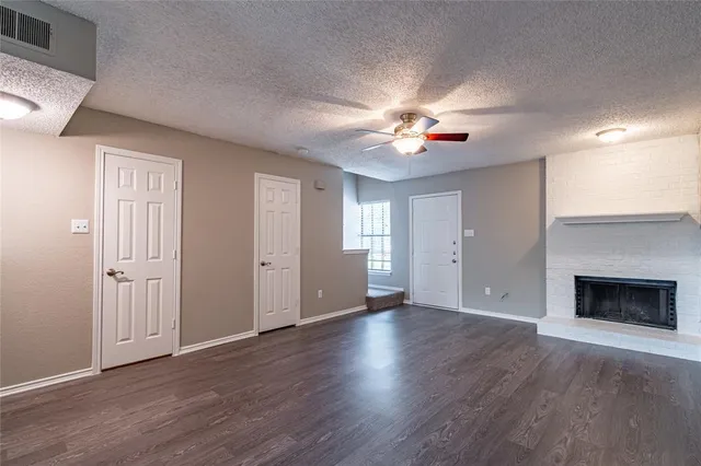 an empty room with wooden floor fireplace and fan