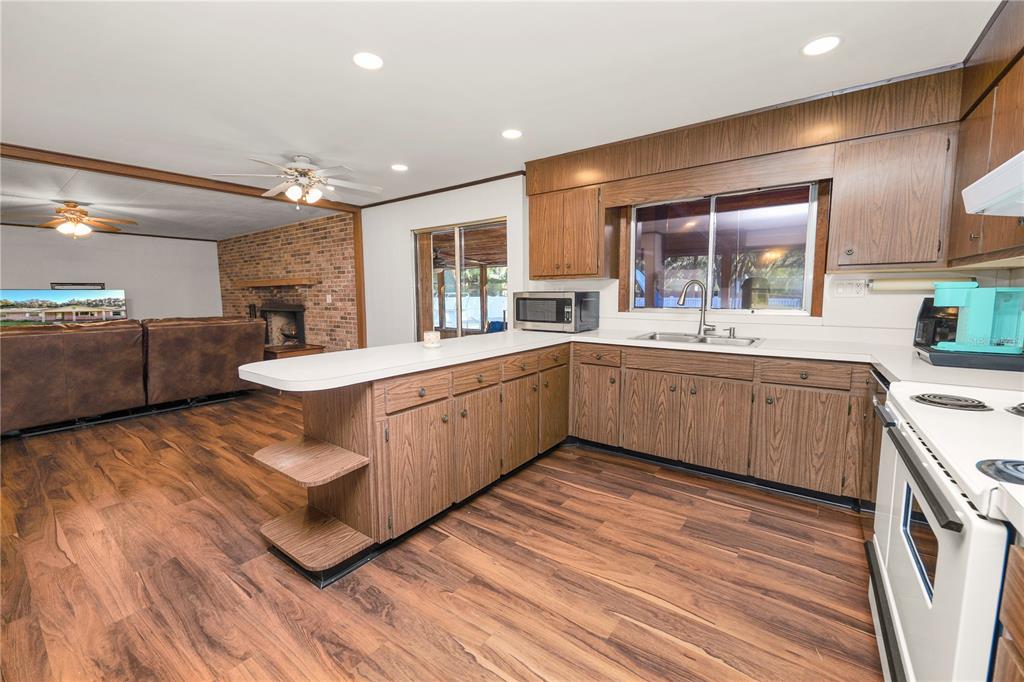 4615 Old Polk City Road Lakeland, FL 33809 - Photo 18 of 71 a large white kitchen with a sink dishwasher a stove and a refrigerator with wooden floor