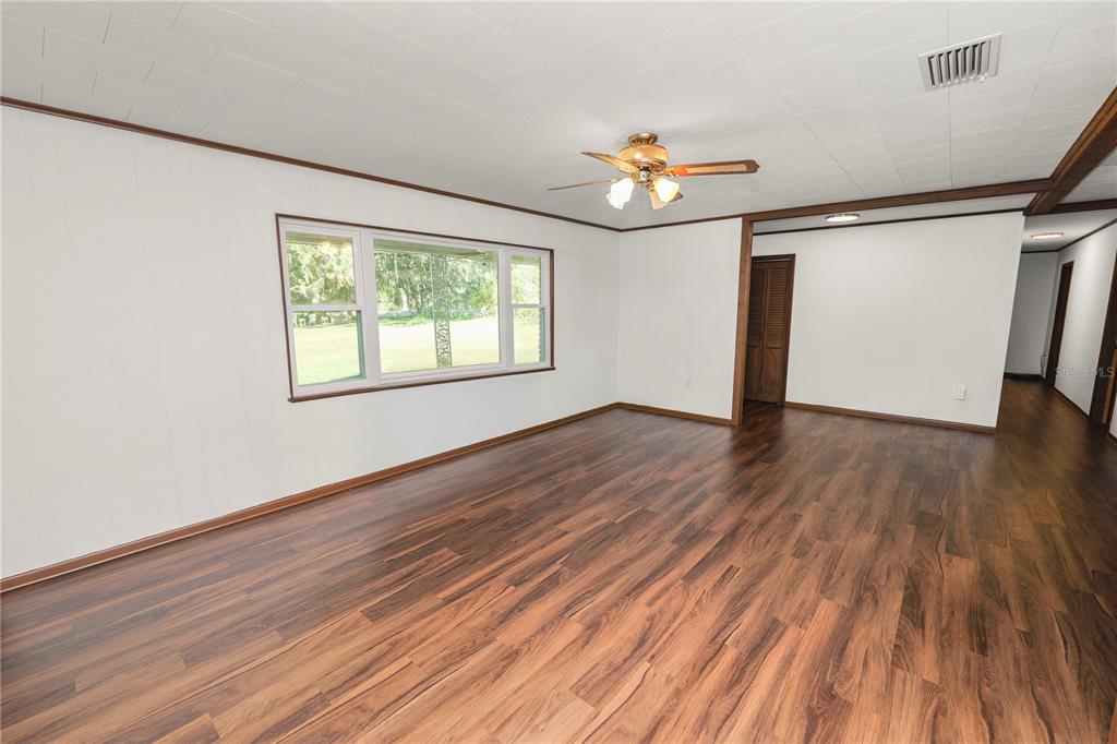 4615 Old Polk City Road Lakeland, FL 33809 - Photo 7 of 71 an empty room with wooden floor chandelier fan and windows