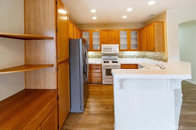 a kitchen with stainless steel appliances granite countertop a refrigerator a stove and a sink with wooden floor