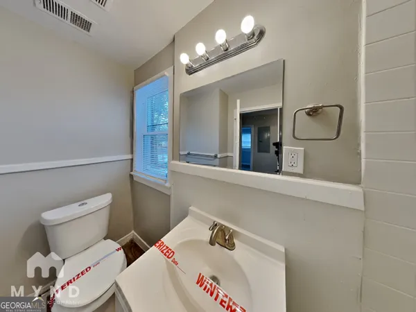 a bathroom with a toilet sink vanity and mirror