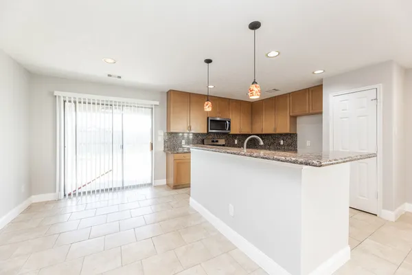 a view of a kitchen with kitchen island stainless steel appliances refrigerator a sink and a stove