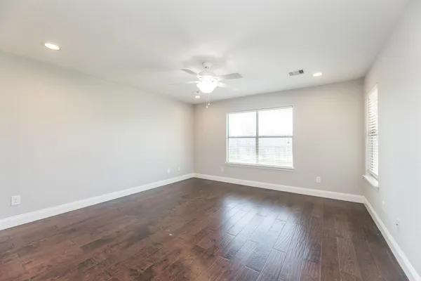an empty room with wooden floor and windows