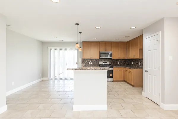 a kitchen with stainless steel appliances granite countertop a refrigerator a sink and white cabinets