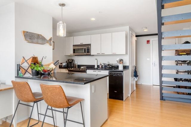 a kitchen with stainless steel appliances kitchen island granite countertop a refrigerator a stove a sink a dining table and chairs with wooden floor