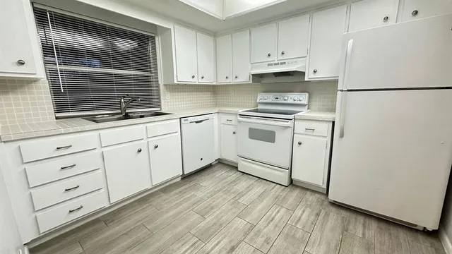a kitchen with granite countertop white cabinets and white appliances