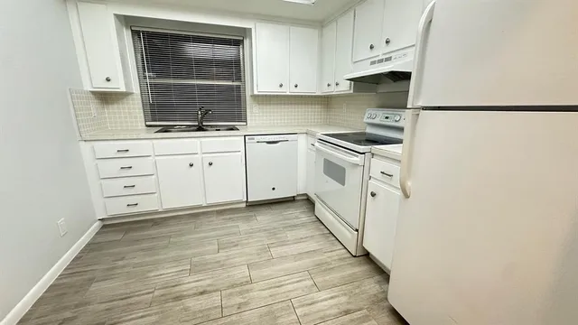a kitchen with granite countertop white cabinets and white appliances