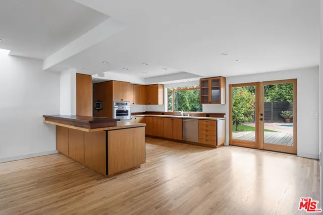 a kitchen with stainless steel appliances kitchen island wooden cabinets and wooden floor