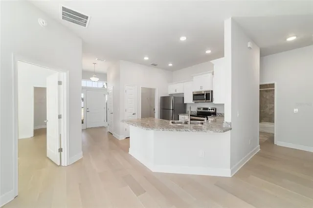 a kitchen with stainless steel appliances granite countertop a refrigerator a stove a sink a stove a oven with white cabinets