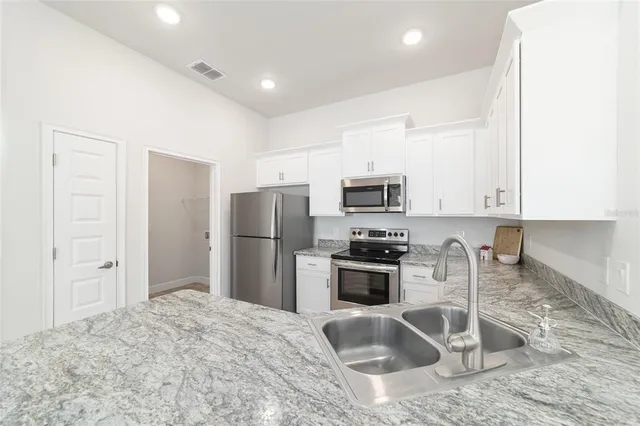a kitchen with granite countertop a refrigerator sink stove and oven