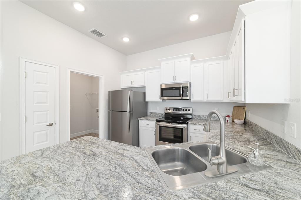 4373 Northeast 31st Street Ocala, FL 34470 - Photo 17 of 51 a kitchen with stainless steel appliances granite countertop a refrigerator a stove a sink a stove a oven with white cabinets