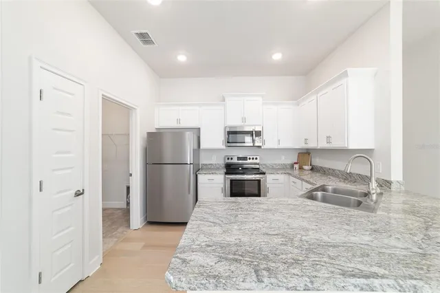 a kitchen with stainless steel appliances granite countertop refrigerator sink and cabinets