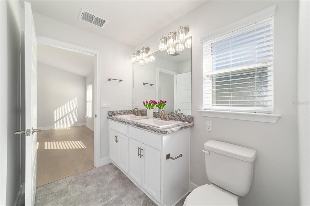 4373 Northeast 31st Street Ocala, FL 34470 - Photo 26 of 51 a en suite bathroom with a granite countertop toilet sink and mirror