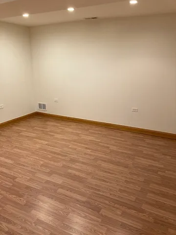 an empty room with wooden floor and fan