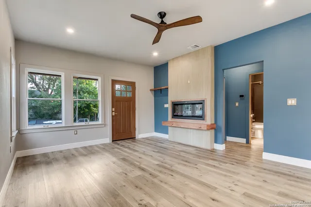 a view of empty room with wooden floor and fan