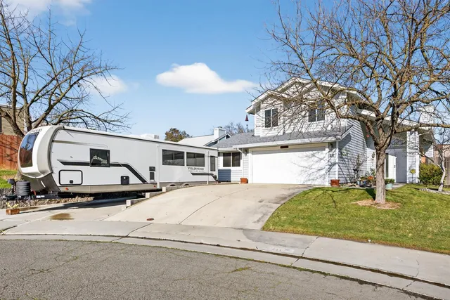 a view of a white house next to a yard with big trees