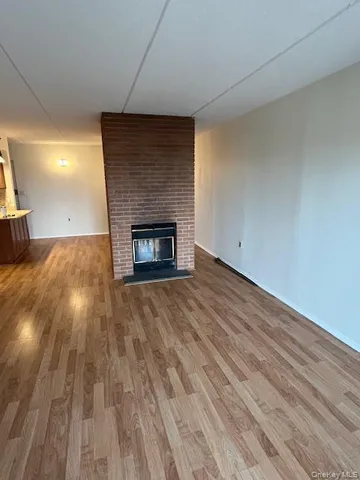 a view of empty room with wooden floor and fireplace