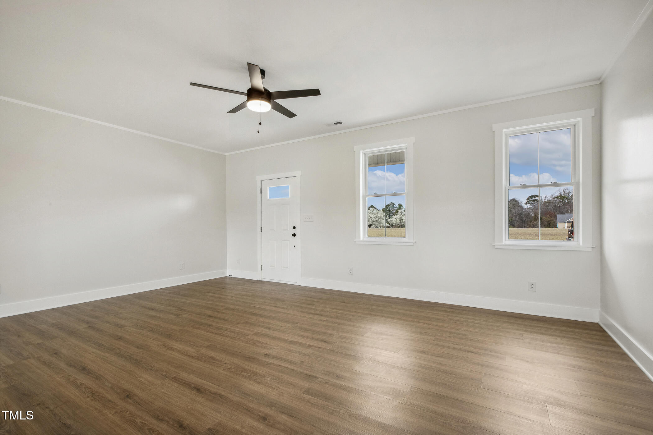 233 Surles Road Benson, NC 27504 - Photo 12 of 57 an empty room with wooden floor ceiling fan and windows