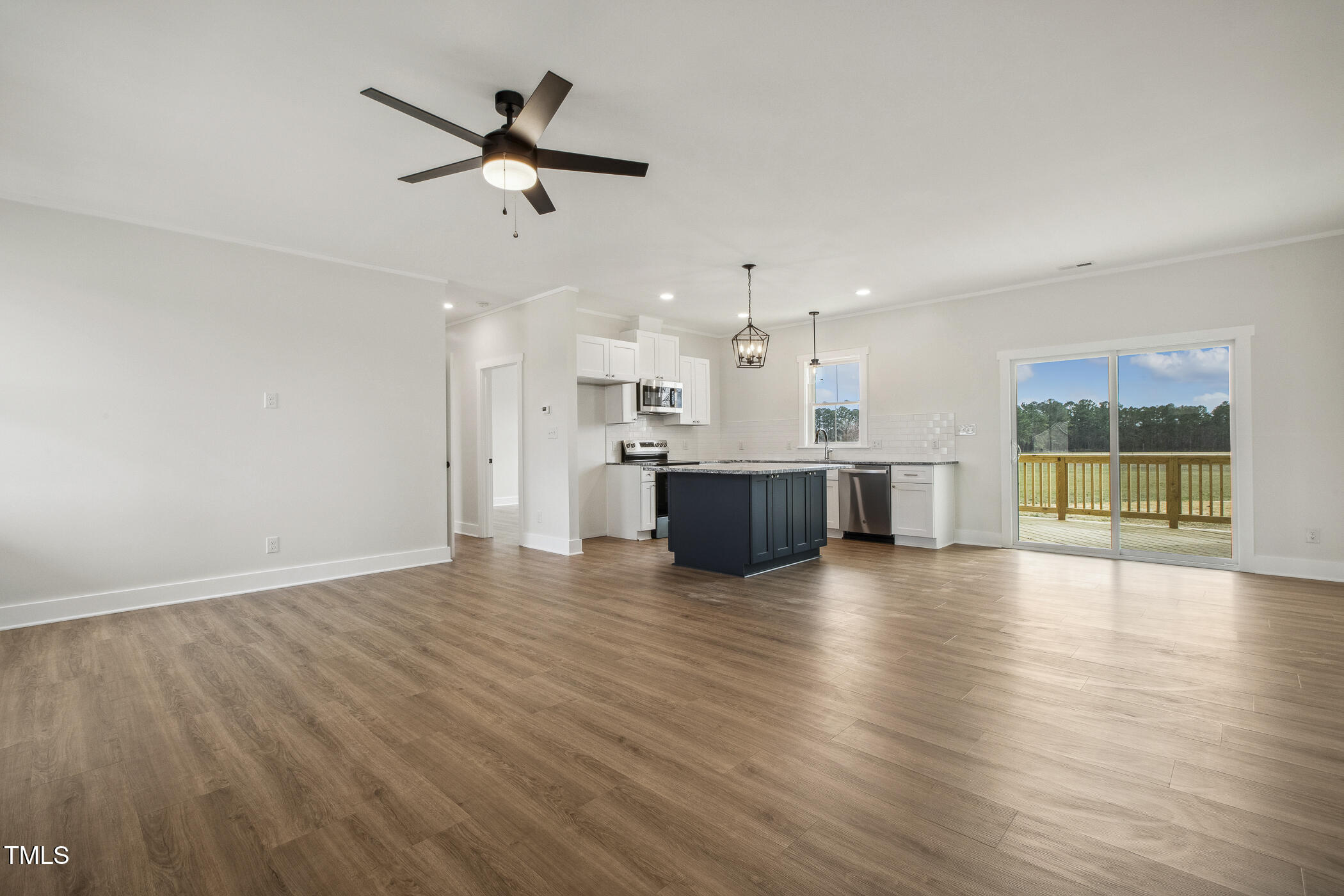 233 Surles Road Benson, NC 27504 - Photo 9 of 57 a view of an empty room with wooden floor and a kitchen