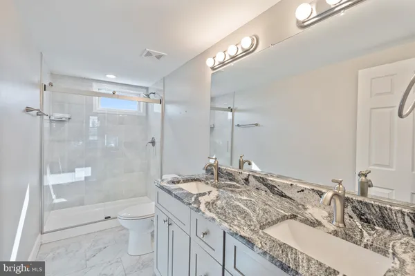 a bathroom with a granite countertop sink a toilet and shower