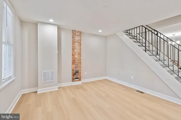 a view of an empty room with wooden floor and stairs
