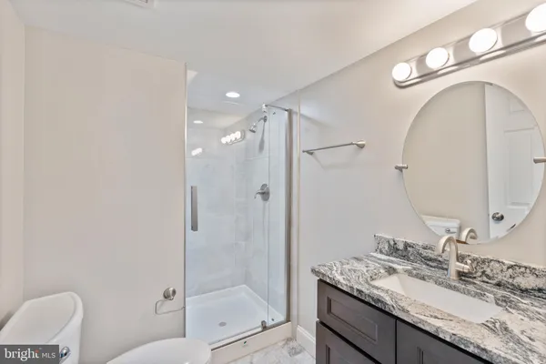a bathroom with a granite countertop sink mirror vanity and toilet