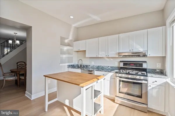 a kitchen with granite countertop a stove a sink and a refrigerator