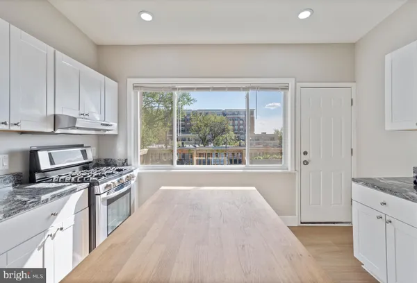 a kitchen with stainless steel appliances granite countertop a stove a sink and a white cabinets