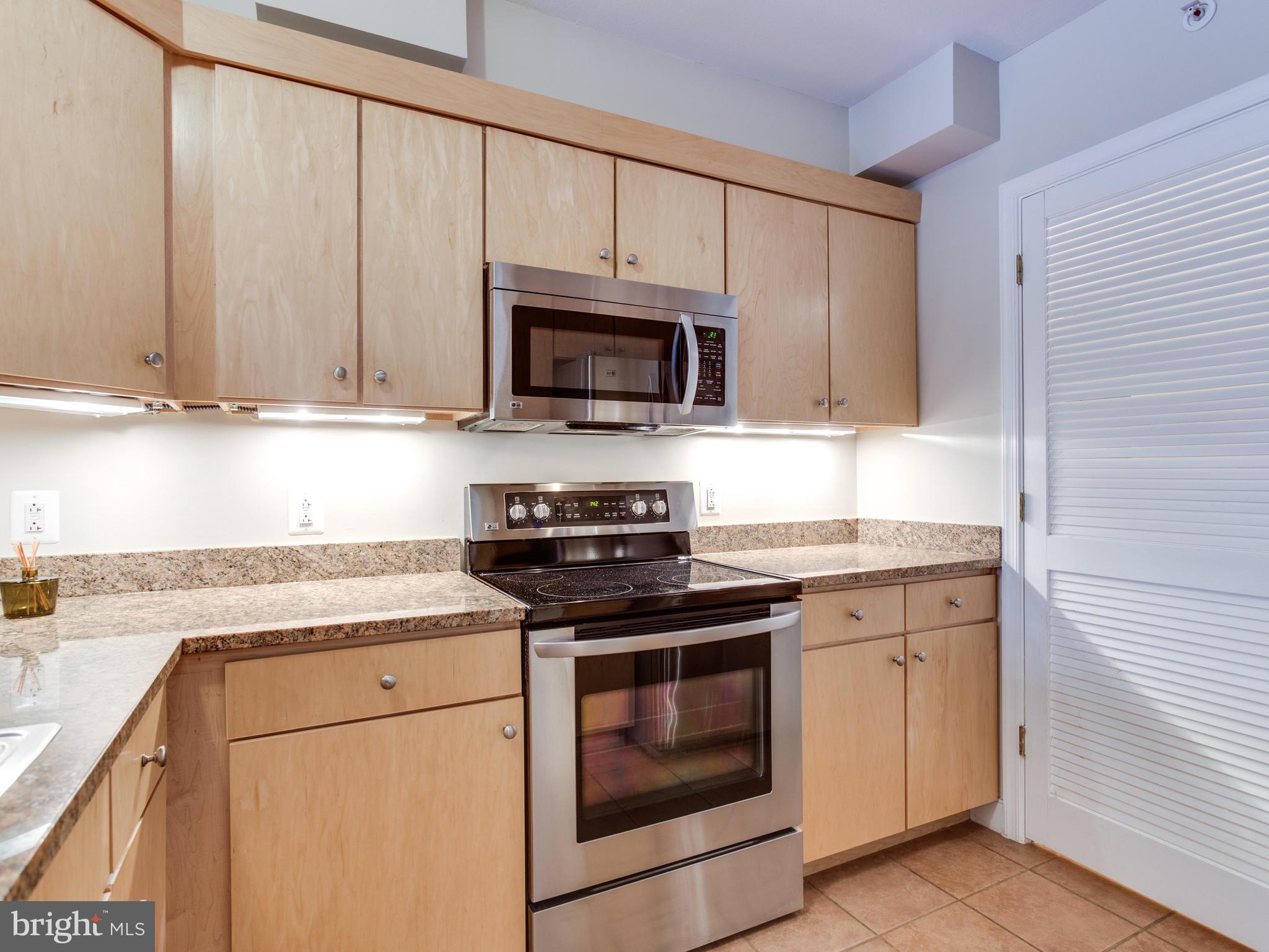 631 D Street Northwest, Unit 837 Washington, DC 20004 - Photo 4 of 29 a kitchen with granite countertop white cabinets and a stove top oven
