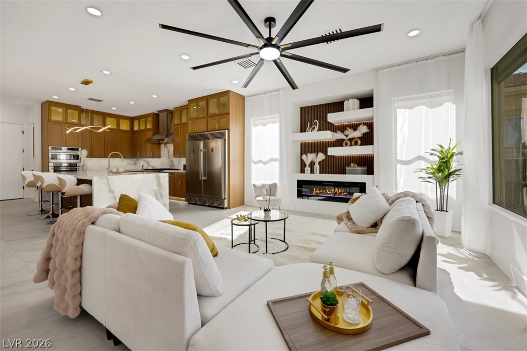 5015 Rivedro Street Las Vegas, NV 89135 - Photo 6 of 91 An open concept living area seamlessly connects a modern kitchen and a cozy entertainment space with a sleek fireplace.