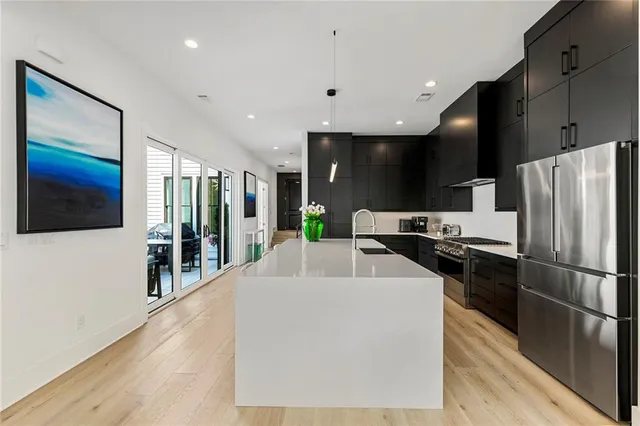 a kitchen with stainless steel appliances a dining table chairs refrigerator and sink