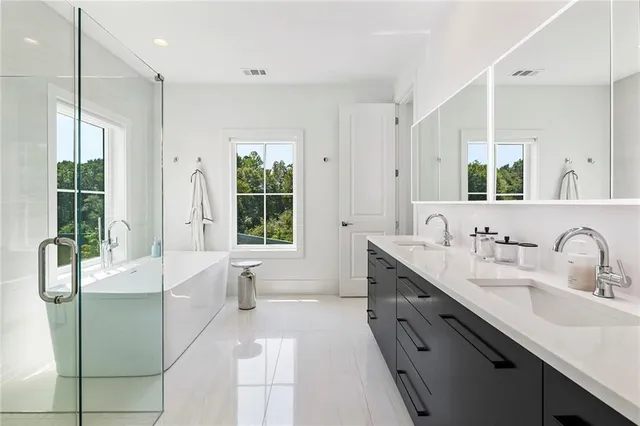 a spacious bathroom with a double vanity sink a large mirror and a bathtub