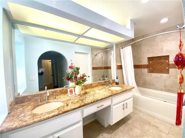 a bathroom with a granite countertop bathtub a sink and a mirror
