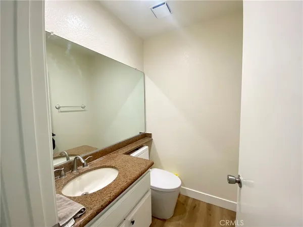 a bathroom with a granite countertop sink toilet and a mirror
