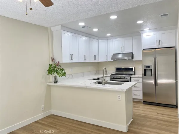 a kitchen with a sink a refrigerator and a stove with wooden floor
