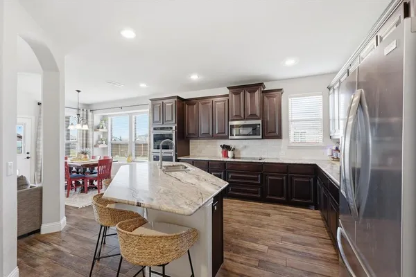 a kitchen with granite countertop a refrigerator and a stove top oven