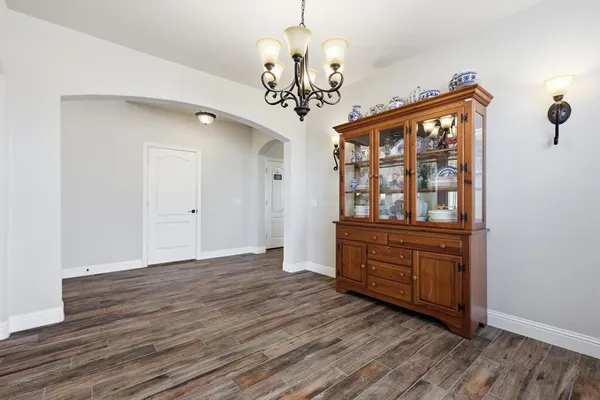 a view of an empty room with chandelier and wooden floor