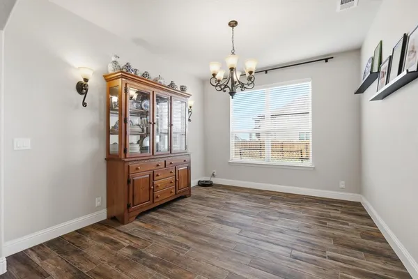 an empty room with wooden floor chandelier and windows
