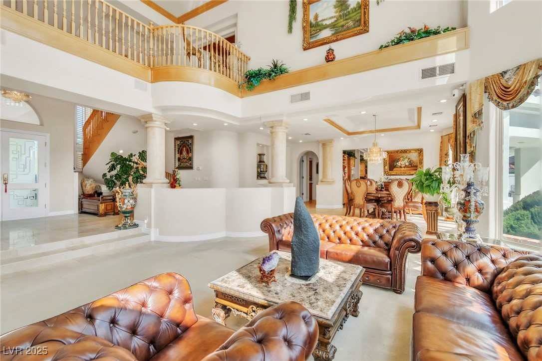 23 Cascade Creek Lane Las Vegas, NV 89113 - Photo 37 of 89 Living area featuring a high ceiling, healthy amount of natural light, decorative columns, arched walkways, and a chandelier