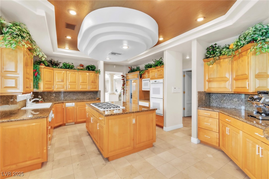 23 Cascade Creek Lane Las Vegas, NV 89113 - Photo 45 of 89 Kitchen with tasteful backsplash, a tray ceiling, dark stone countertops, recessed lighting, and a center island