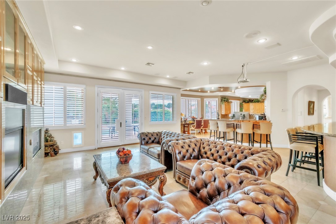 23 Cascade Creek Lane Las Vegas, NV 89113 - Photo 52 of 89 Living room with recessed lighting, arched walkways, light tile patterned floors, a high end fireplace, and french doors